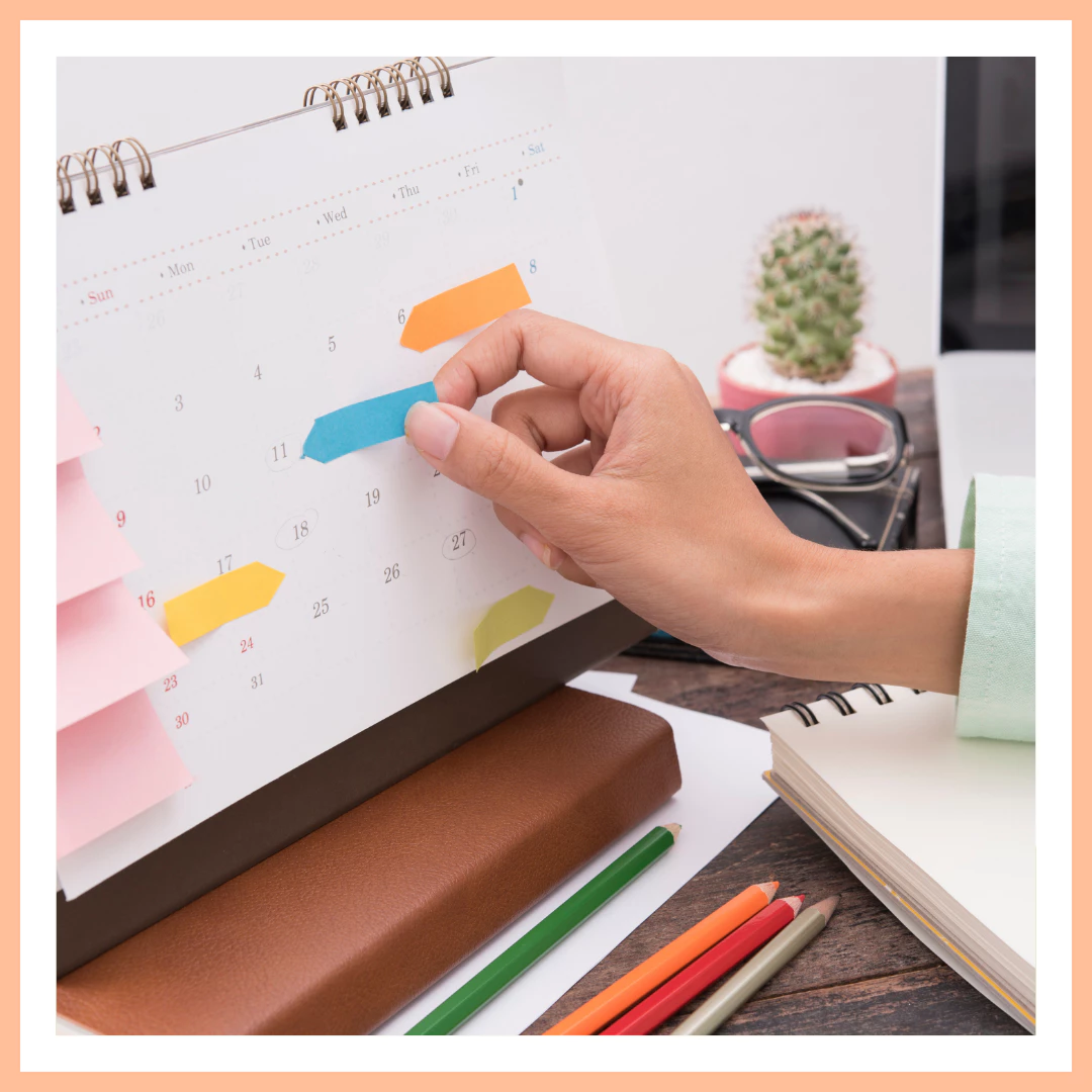 Formation gestion du temps – Planifier sa communication efficacement Main posant une étiquette colorée sur un calendrier papier, outil de planification dans le cadre d’une formation en gestion du temps